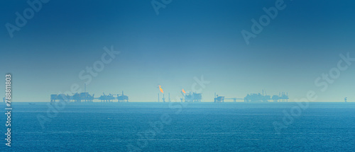 Foto Panoramic view of the sea surface, oil rigs with burning fire are visible on the