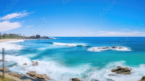 Amazing view of the California coastline. The blue waves crash against the rocky shore, while the white clouds dot the bright blue sky. © BozStock