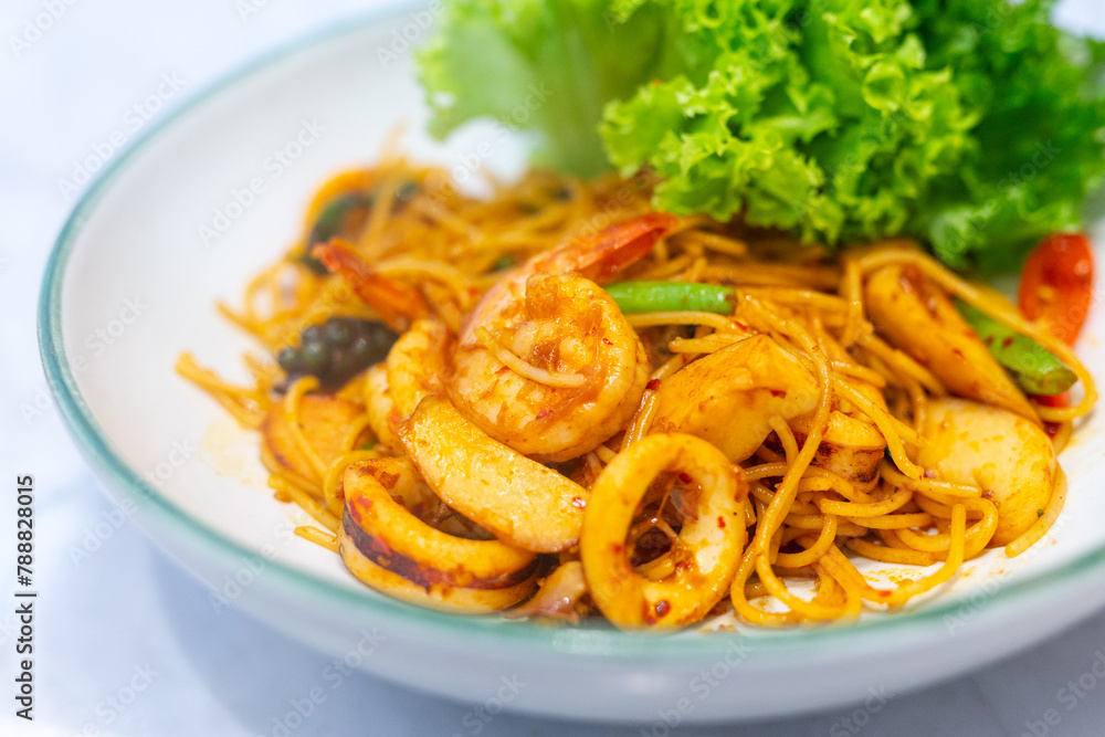 Closeup Spaghetti Tom Yum Seafood in white plate in a restaurant Closeup Spaghetti Tom Yum Seafood in white plate in a restaurant