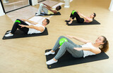 Young adult people practicing pilates with ball at group class in yoga studio