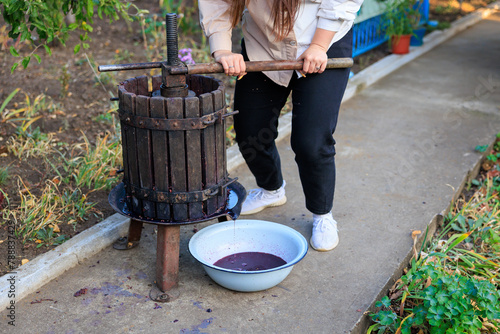 A woman works with a press to produce homemade farm wine. Background with selective focus photo