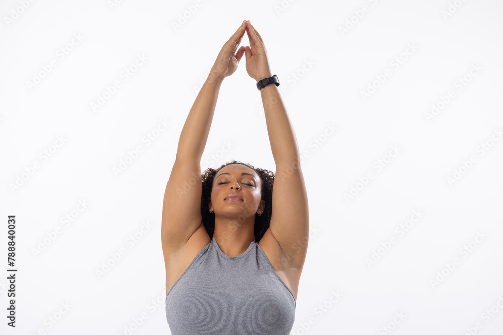 Naklejka premium Biracial young female plus size model stretching arms above head, eyes closed, on white background