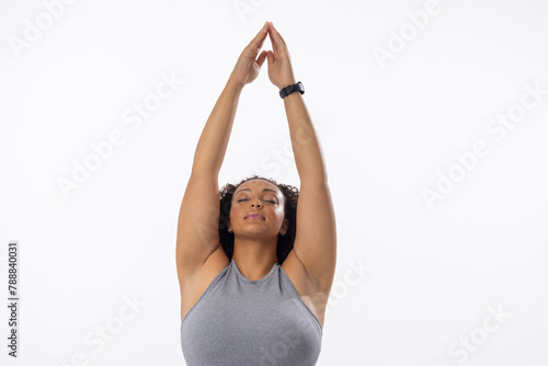 Biracial young female plus size model stretching arms above head, eyes closed, on white background © wavebreak3