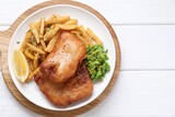 Tasty fish, chips, peas and lemon on white wooden table, top view
