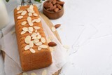 Cake with fresh almond flakes and nuts on white textured table, closeup. Space for text