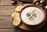 Fresh homemade mushroom soup in ceramic bowl on wooden table. Space for text