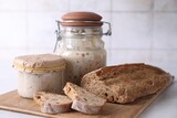 Sourdough starter in glass jars and fresh bread on light table