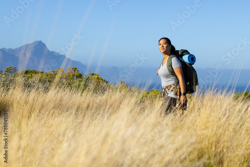 Biracial female hiker standing in tall grass, copy space photo