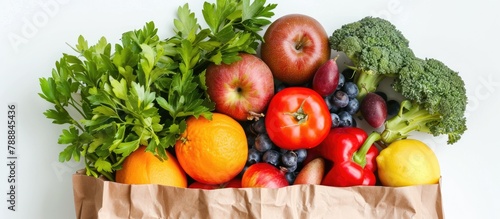 An assortment of healthy foods packed in a paper bag, isolated on a white background and seen from above.