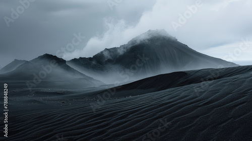 Dramatic black sand dunes rising against a backdrop of mountain silhouettes and cloudy skies