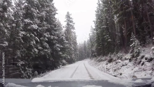 Driving down a snow covered mountain forest road with pine trees and a camp ground in the Bighorn Mountains 