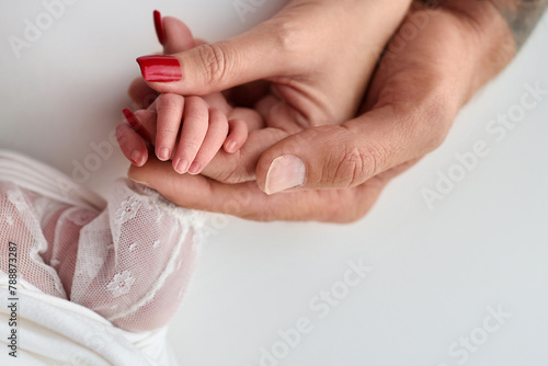 Close-up little hand of child and palm of mother and father. The newborn baby has a firm grip on the parent's finger after birth. A newborn holds on to mom's, dad's finger.