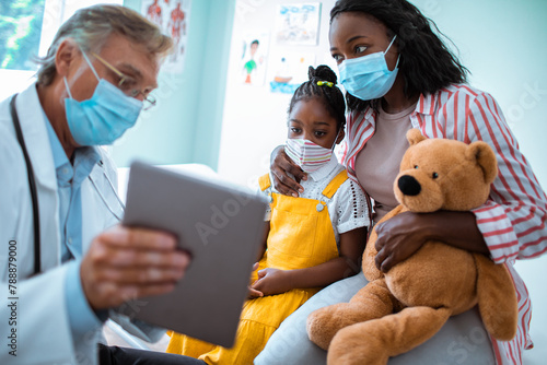 Mother and daughter wearing face masks at pediatrician's appointment photo