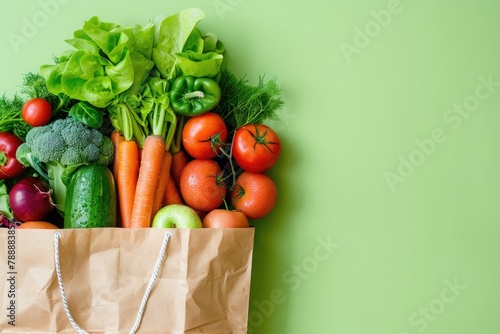 Paper bag full of fresh organic vegetables on green background. Healthy food shopping concept