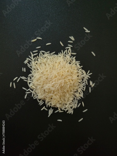 Cluster of white rice grains arranged on top of a sleek black table, creating a stark contrast. 