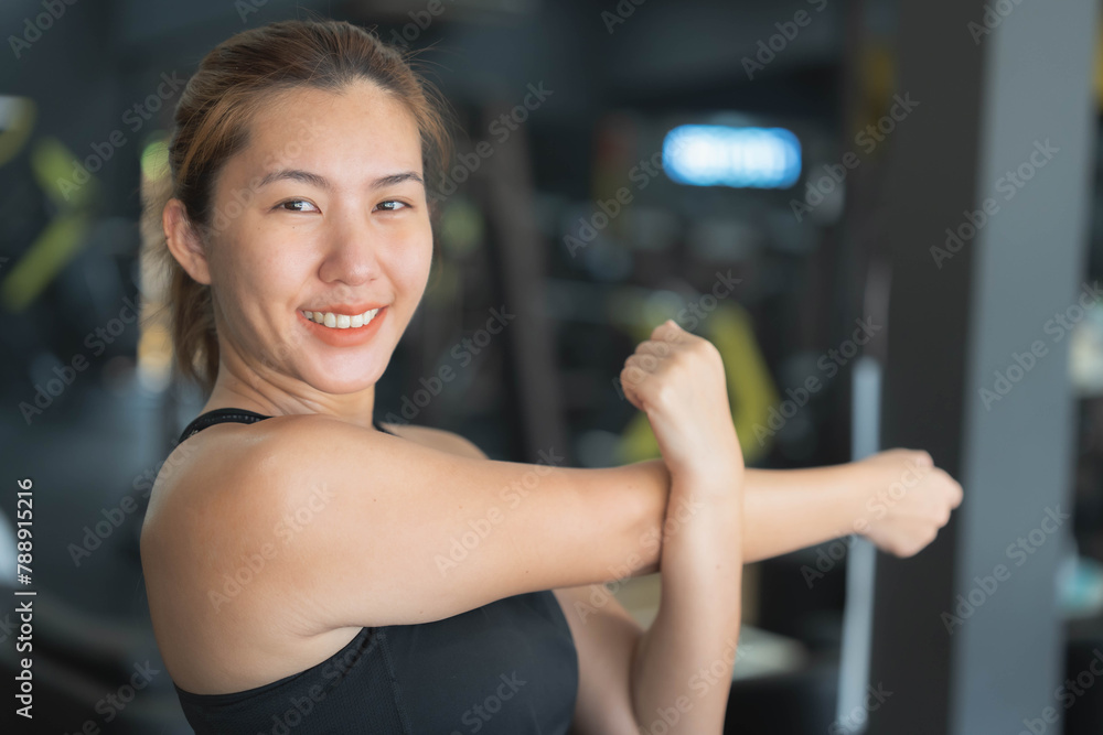 Asian woman stretching her muscles before exercising at the fitness center. Health care concept, playing sports, weight training, losing weight, building muscle.