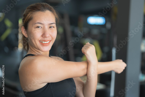 Asian woman stretching her muscles before exercising at the fitness center. Health care concept, playing sports, weight training, losing weight, building muscle. © Worranan