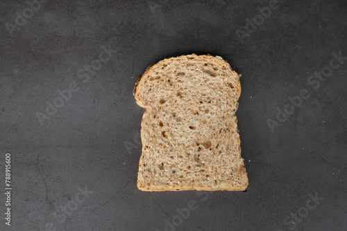 Top view of a piece of grain loaf bread on balck background