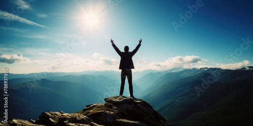 Raising arms on top of mountain with blue sky and sunlight The concept of being a successful leader with goals, growth, and upwards. © ORG