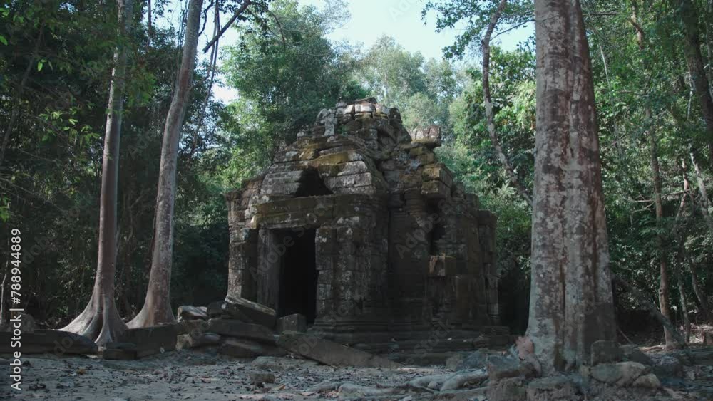 Ancient temple ruins of Angkor Wat surrounded by jungle, stone structure with trees Ancient temple ruins of Angkor Wat surrounded by jungle, stone structure with trees