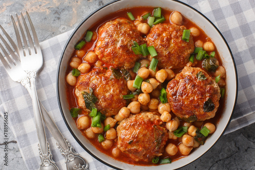 Mediterranean food Lamb meatballs served with chickpeas, tomato and green onions close-up in a bowl on the table. Horizontal top view from above