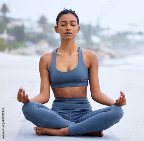 Yoga, lotus meditation and woman at beach for mindfulness, peace and calm at sea to relax. Zen, ocean and padmasana pose for exercise, fitness and wellness for body of healthy Indian girl outdoor