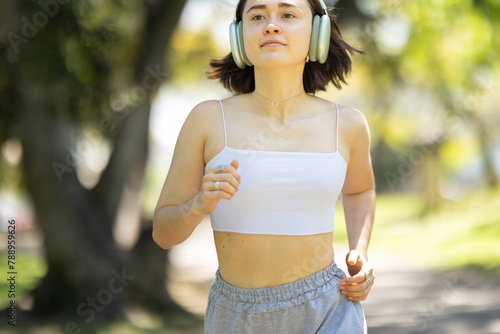 A woman is running in a park with her headphones on