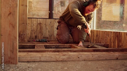 Man Hammering Nails On The Wood Brace Of Flooring. - static shot photo