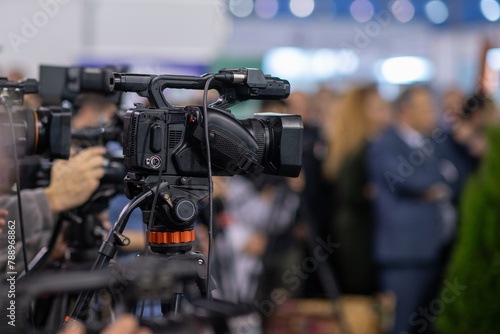 A camera lens captures the essence of a press conference, highlighting media coverage and journalism in action © Microgen