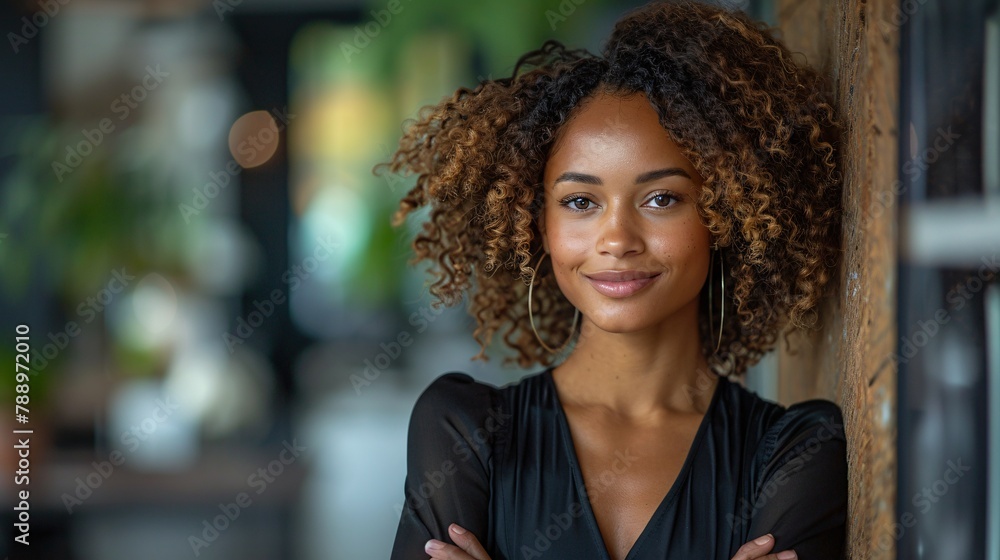 A poised and self-assured female executive stands with arms folded against a wall in her workplace. A poised and self-assured female executive stands with arms folded against a wall in her workplace.