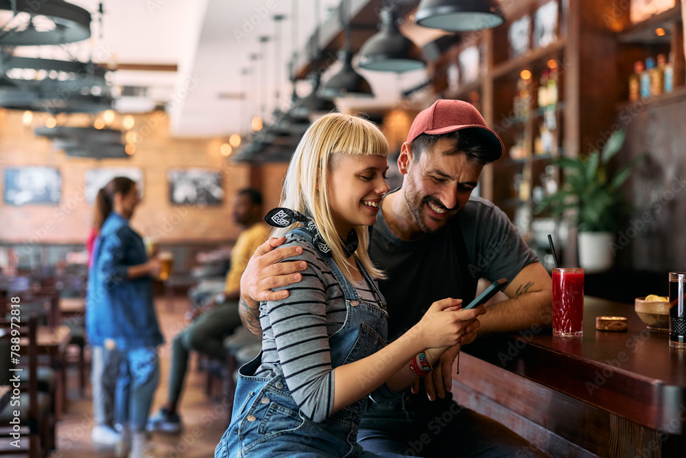Young happy couple using smart phone at bar counter. Young happy couple using smart phone at bar counter.