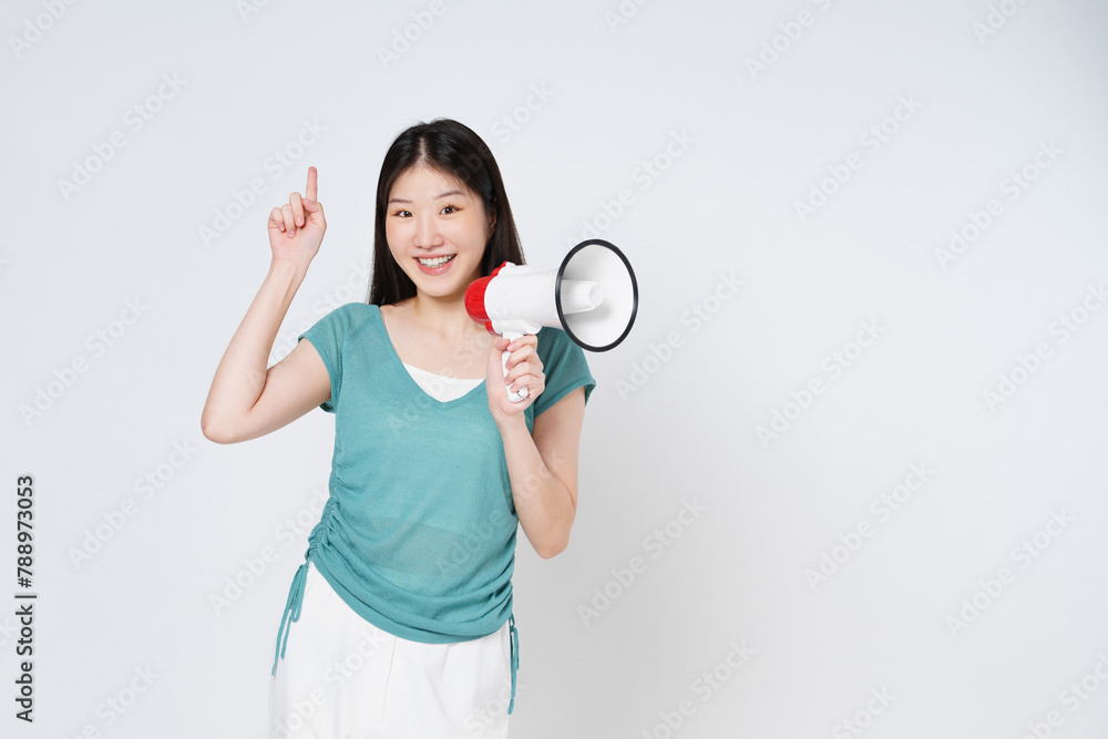 Smiling happy asian girl holding megaphone and pointing up, announcing discount promo, showing advertisement on top, standing over white background. Smiling happy asian girl holding megaphone and pointing up, announcing discount promo, showing advertisement on top, standing over white background.