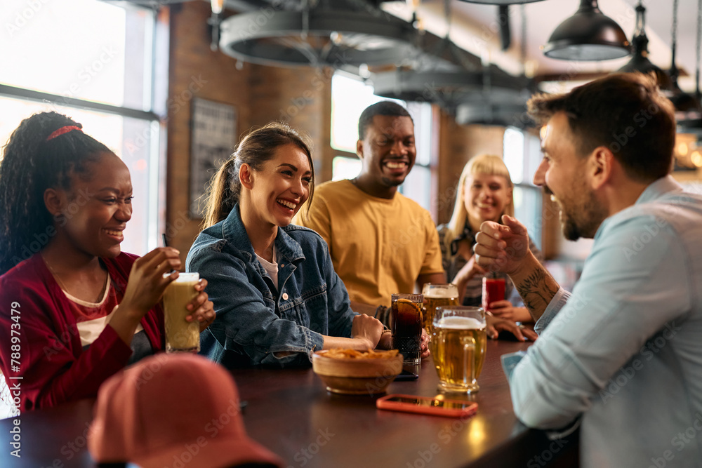 Multiracial group of happy friends communicating while gathering in pub.