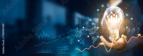 Businessman holding creative light bulb with growth graph, analytics icons. Utilizing analytics technology to develop new strategies and insights that enhance successful performance in global business