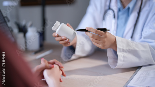 Asian psychologist women pointing on pills bottle to explaining medicine and prescription to female patient while giving counseling about medical and mental health therapy to female patient in clinic