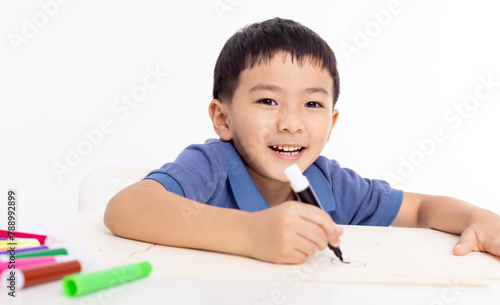 Smiling asian child schoolboy studying and drawing at home