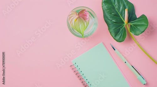 Green paper spiral notepad with anthurium or flamingo flower pen and glass of water on the pink background Business concept flat lay card Copy space : Generative AI photo