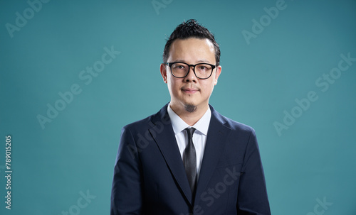 Confident businessman with glasses on teal background