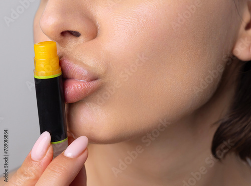 portrait of young woman using natural ingredients home made lip balm and cream.girl applying on lips and cheeks.facial cosmetic from oils, lemon and cocoa butter.smiling female holding bottle on face.