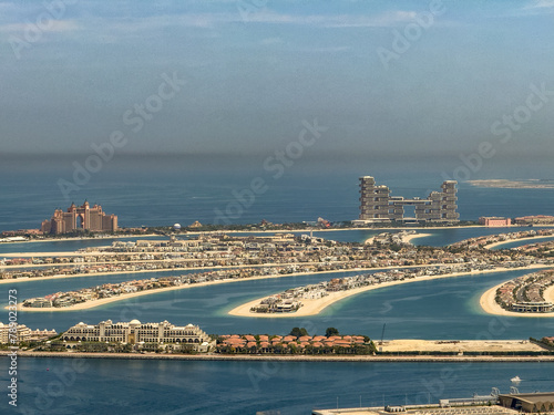 aerial city view of Dubai with the artificial island Palm Jumeirah, with many famous buildings along the coastline of The Palm 