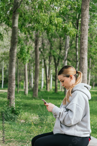 A woman rests during a walk to send a message with her phone