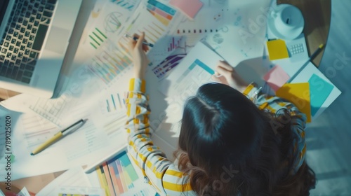 stylish young girl working  analytics holding pen on craft background with laptop and papers flat lay : Generative AI photo