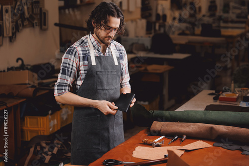 Portrait happy tailor working with natural brown leather in workshop. Small business of shoemaker cobbler