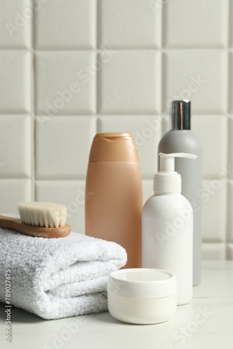 Different bath accessories and personal care products on white table near tiled wall