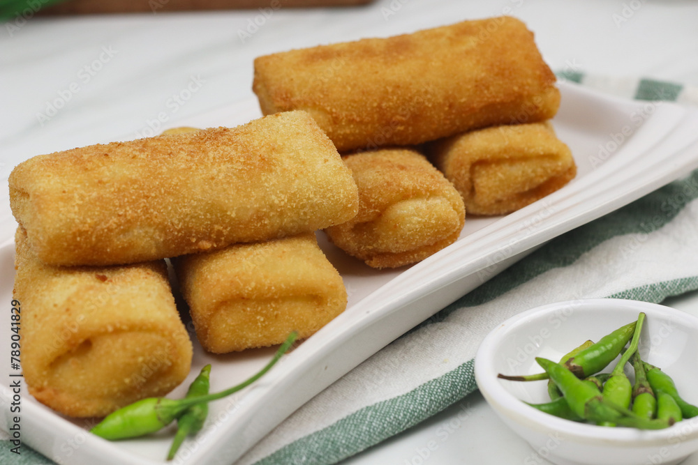 Risoles, one of Indonesian popular snack. Made from crepe skin filled with vegetables, chicken, coated with bread crumbs and deep fry. White marble background. Risoles, one of Indonesian popular snack. Made from crepe skin filled with vegetables, chicken, coated with bread crumbs and deep fry. White marble background.