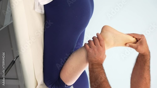 Physiotherapist hands examines patient knee flexion and ankle mobility. Vertical