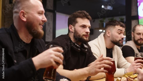 Friends are sitting in a bar, watching a broadcast of a football match, drinking beer. Victory and defeat in the game. Concept for sport competition, hobby, lifestyle, human emotion, fun