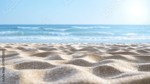 The beach background with smooth fine sand that is softly colored, turquoise waves lap a soft sand beach beneath a bright blue sky. © Pro Hi-Res