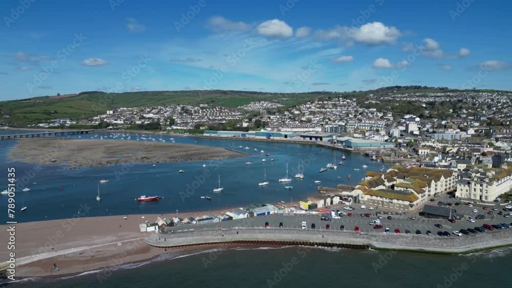 Teignmouth, South Devon, England: DRONE VIEWS: The drone circles Teignmouth and the River Teign estuary showing the pier and river bridge. Teignmouth is a popular UK holiday destination (Clip 5). Teignmouth, South Devon, England: DRONE VIEWS: The drone circles Teignmouth and the River Teign estuary showing the pier and river bridge. Teignmouth is a popular UK holiday destination (Clip 5).