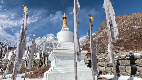 Buddhist enlightenment Stupa in surrounded by white prayer flag. High Himalayan summits against a blue sky. Nepal, Langtang Trek photo